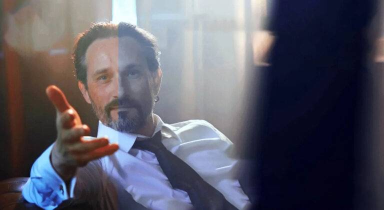 A video still image of a man with his had outstretched. The image is split, with one side showing colour correction using Adobe Premiere Pro